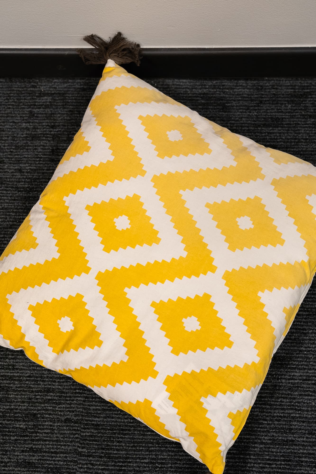 coussin blanc a motifs losanges jaune avec pompons