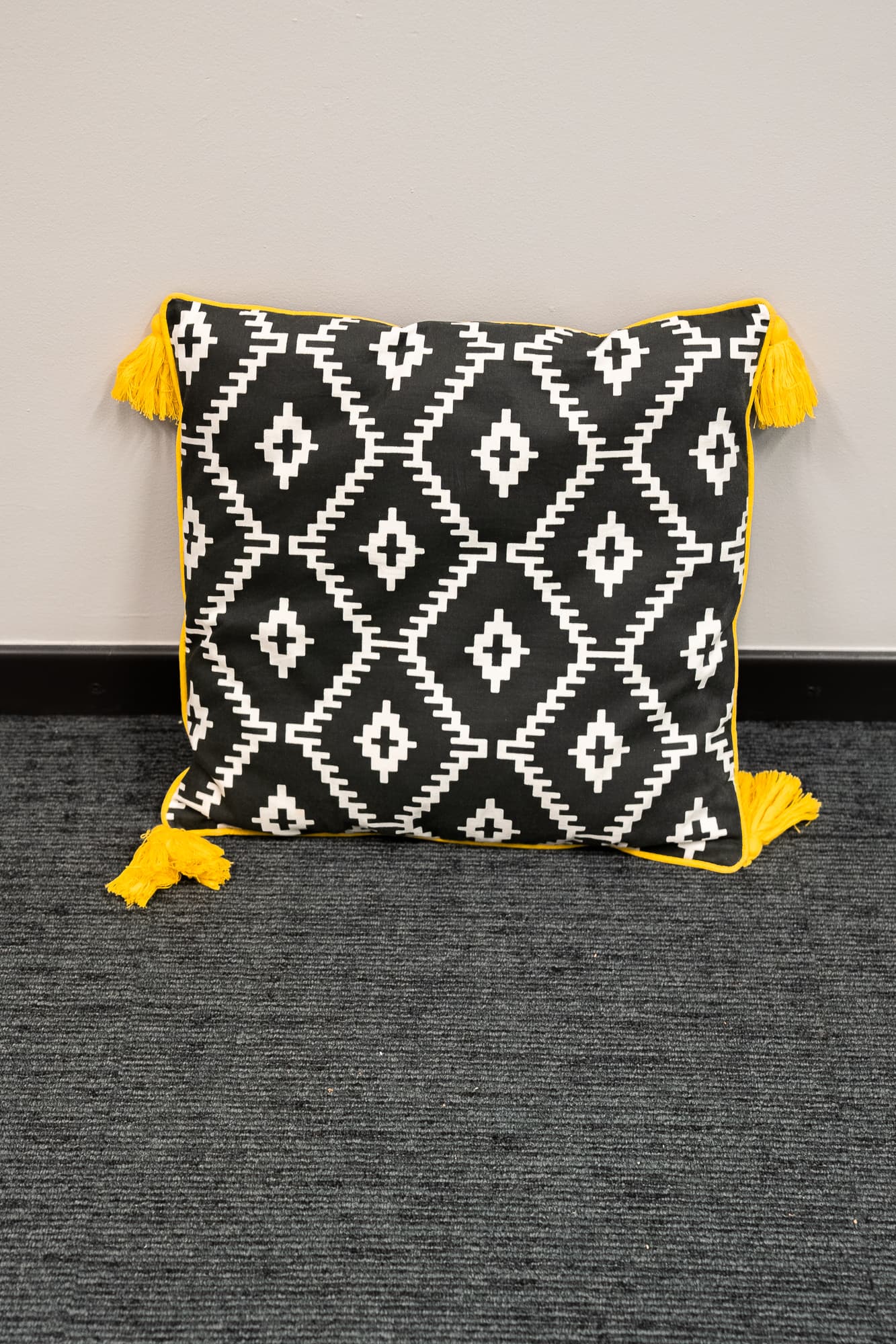 coussin noir motifs losanges blanc avec pompons